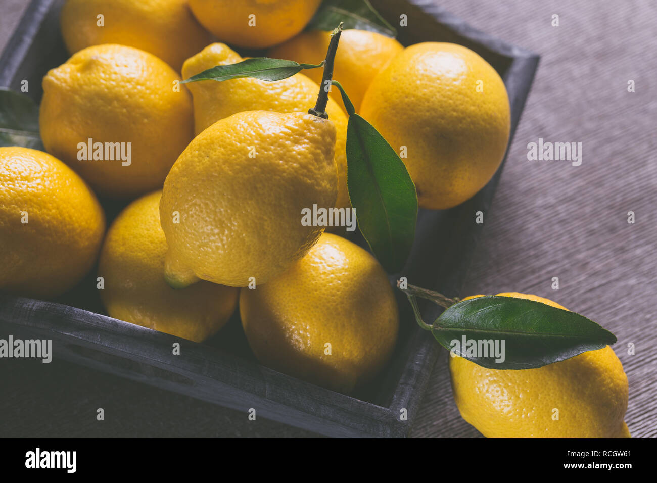 Citrons jaunes juteux frais avec des feuilles sur la table en bois. Banque D'Images