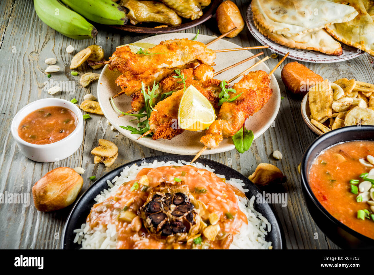 Concept alimentaire en Afrique de l'Ouest. Wset traditionnels mets africains assortiment - soupe d'arachides, de riz jollof, ailes de poulet grillées à sec, les plantains, bananes frites Banque D'Images