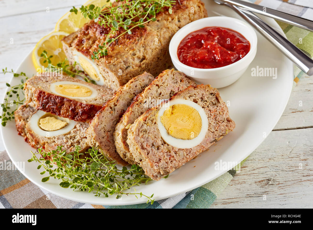 Viande farcies avec oeuf dur servi avec une sauce tomate et des rondelles de citron sur une plaque blanche sur une vieille table en bois, vue horizontale à partir de ci-dessus, Banque D'Images