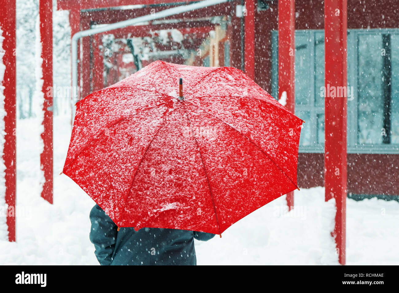 Triste et seule femme parapluie rouge sous la neige en hiver grâce à l'environnement urbain Banque D'Images