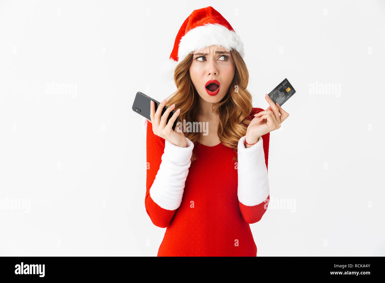 Image d'une belle femme choqué en costume noël holding credit card et le téléphone mobile. Banque D'Images