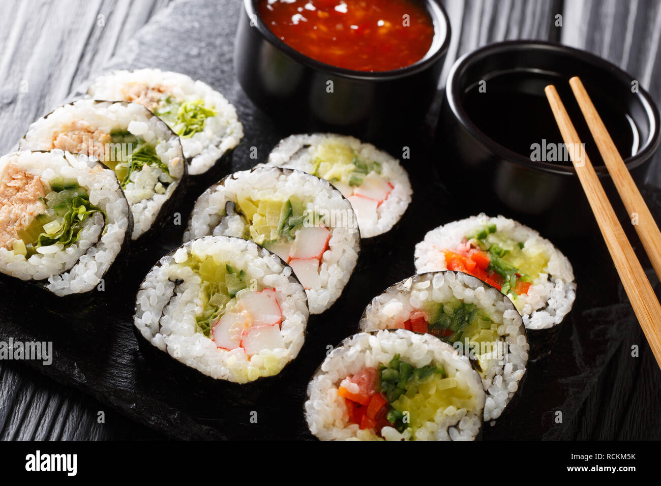 Ensemble de rouleaux futomaki japonais avec le soja et les sauces chili close-up sur une liste de sélection sur la table horizontale. Banque D'Images