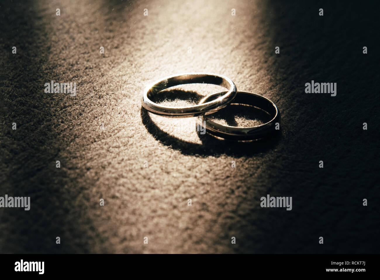 Deux anneaux de mariage se trouvent à côté du tapis, et le rayon de lumière s'allume en eux Banque D'Images