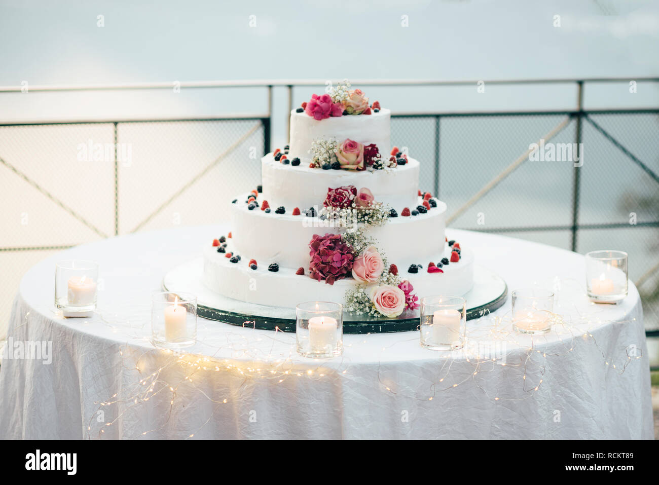 Un beau gâteau de mariage à quatre niveaux est sur la table dans le contexte du pittoresque lac Banque D'Images