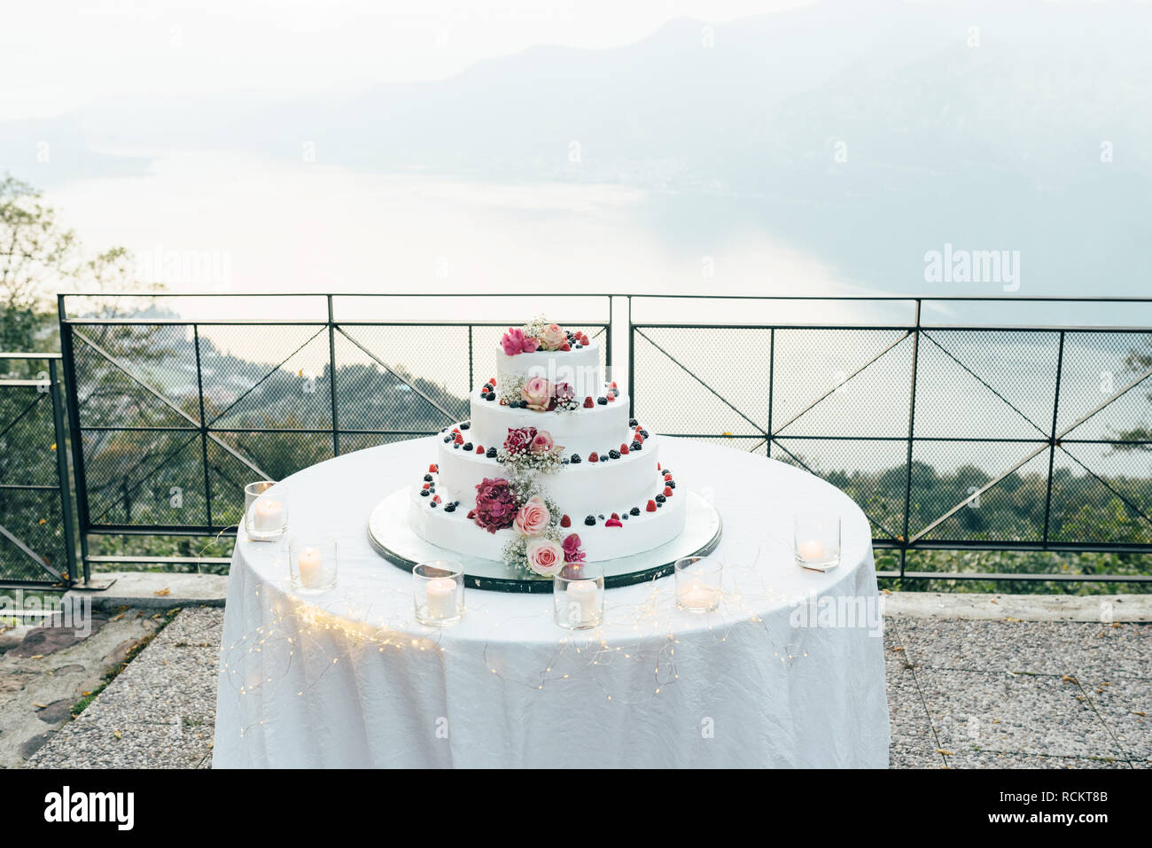 Un beau gâteau de mariage à quatre niveaux est sur la table dans le contexte du pittoresque lac Banque D'Images
