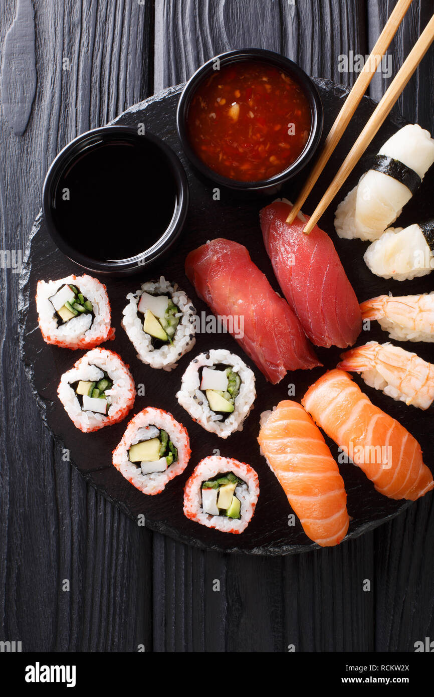 Ensemble de rouleaux japonais d'uramak nigiri et servi avec deux sauces close-up sur une plaque en ardoise. Haut Vertical Vue de dessus Banque D'Images