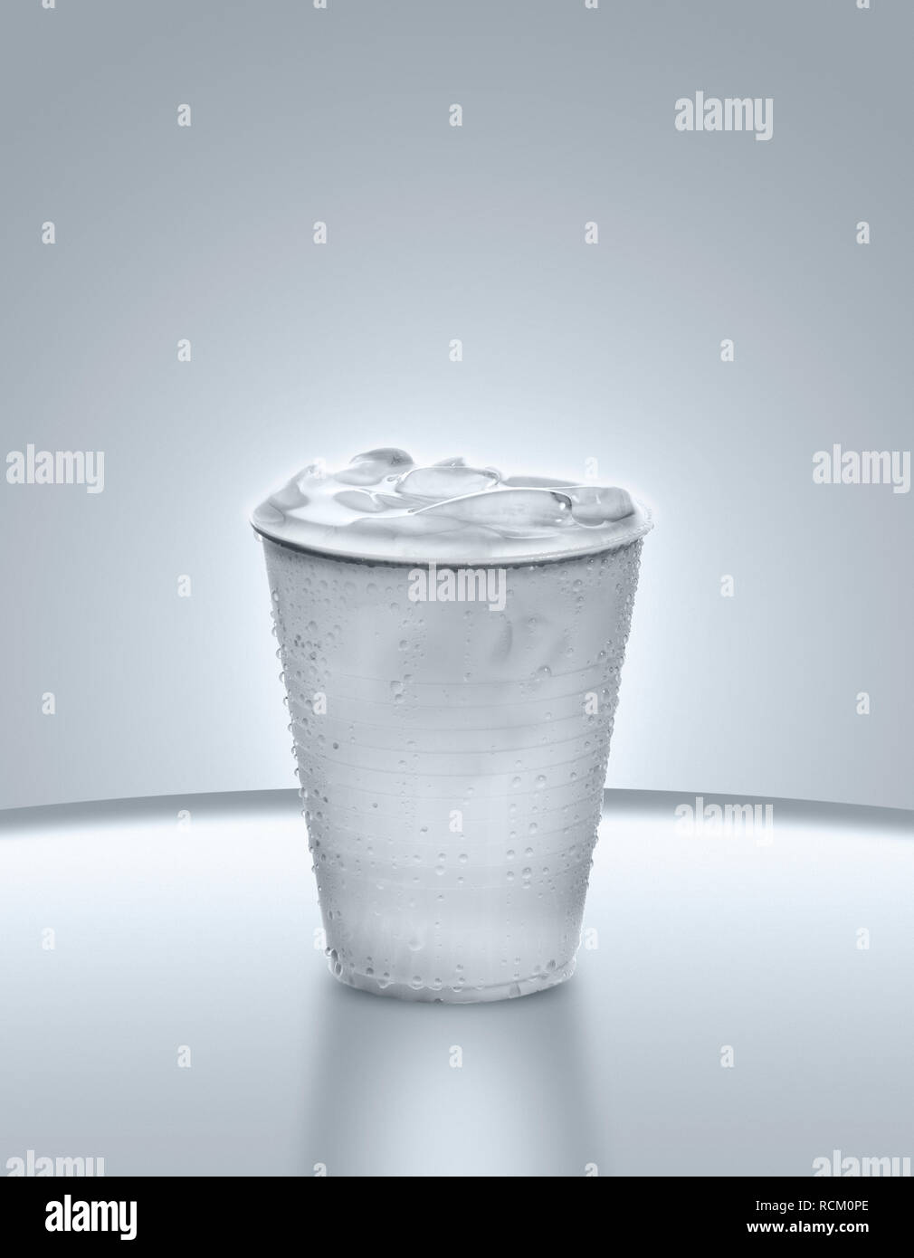Gobelet plastique jetable plein d'eau et de glace, fond gris, Close up Banque D'Images