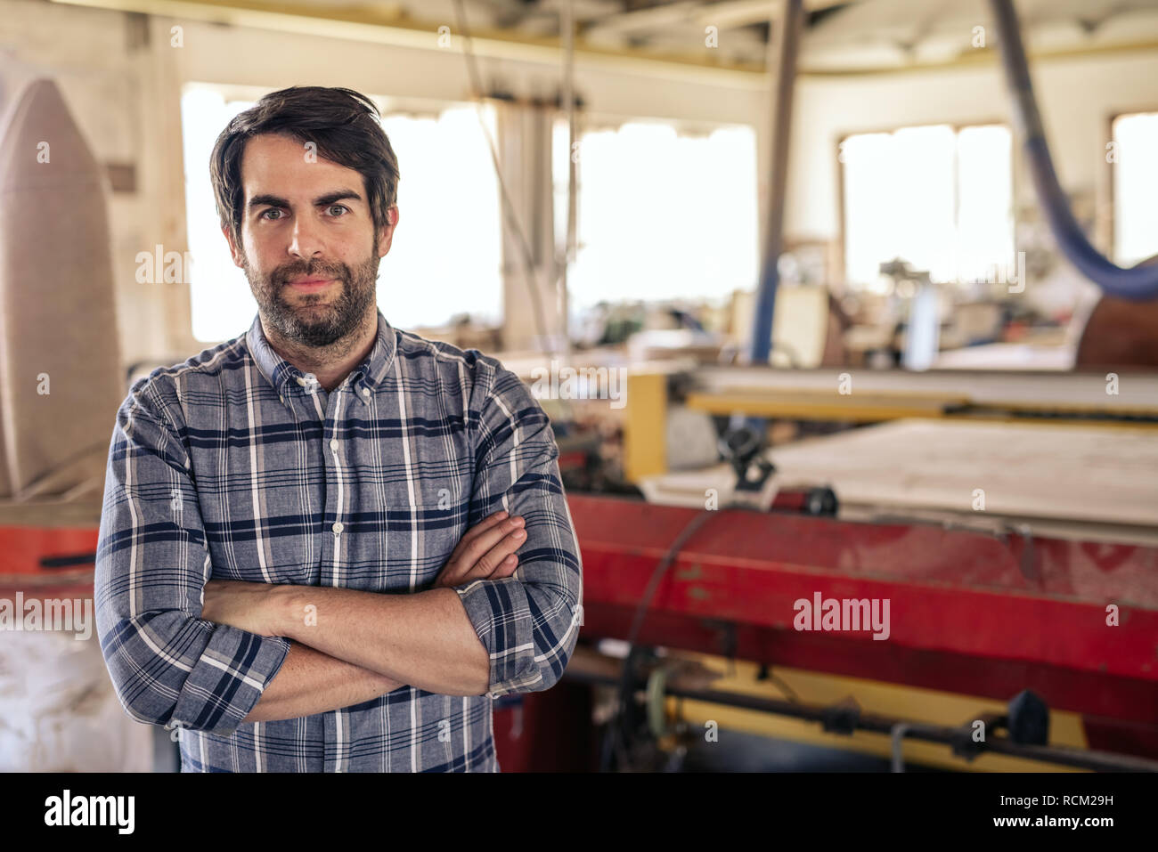 Carpenter debout avec les bras croisés dans un atelier de menuiserie Banque D'Images