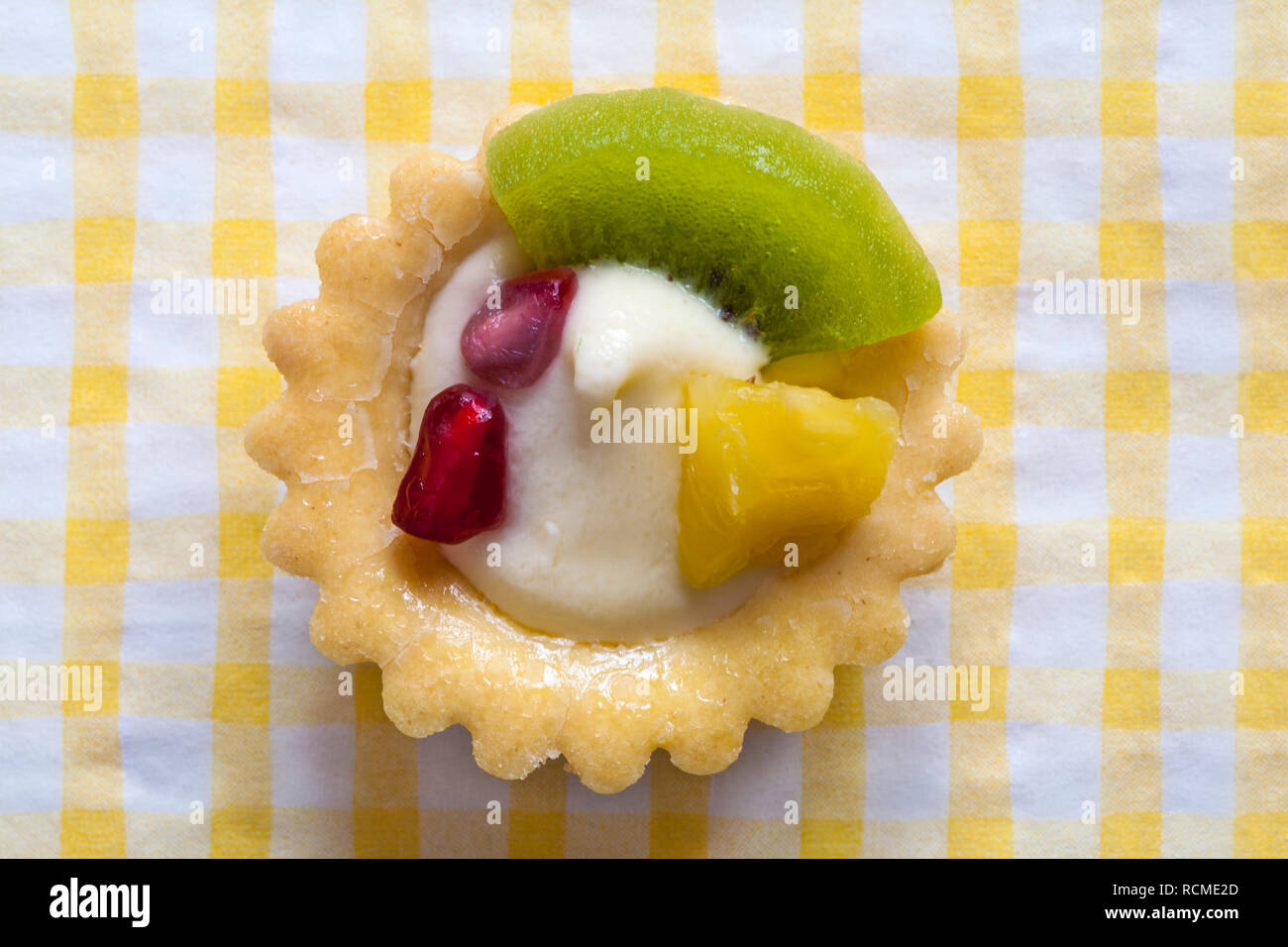 M&S mini tarte aux fruits avec kiwi, ananas et graines de grenade situé sur jaune et blanche serviette serviette vérifié Banque D'Images