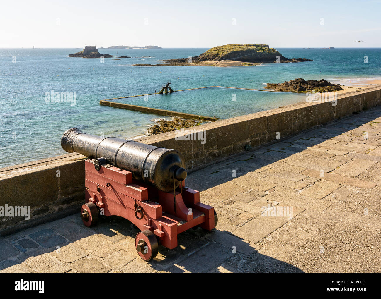 La piscine de marée à Saint-Malo, France, au coucher du soleil avec un vieux canon en premier plan et le Grand Être et Petit îles au loin. Banque D'Images