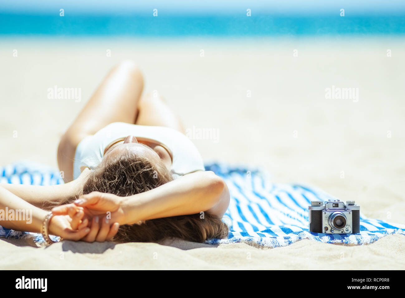 Vus de derrière l'appareil photo rétro et d'une femme portant sur une serviette à rayures sur la rive de l'océan. Locations de capture de photos incroyables préserver ces memor Banque D'Images