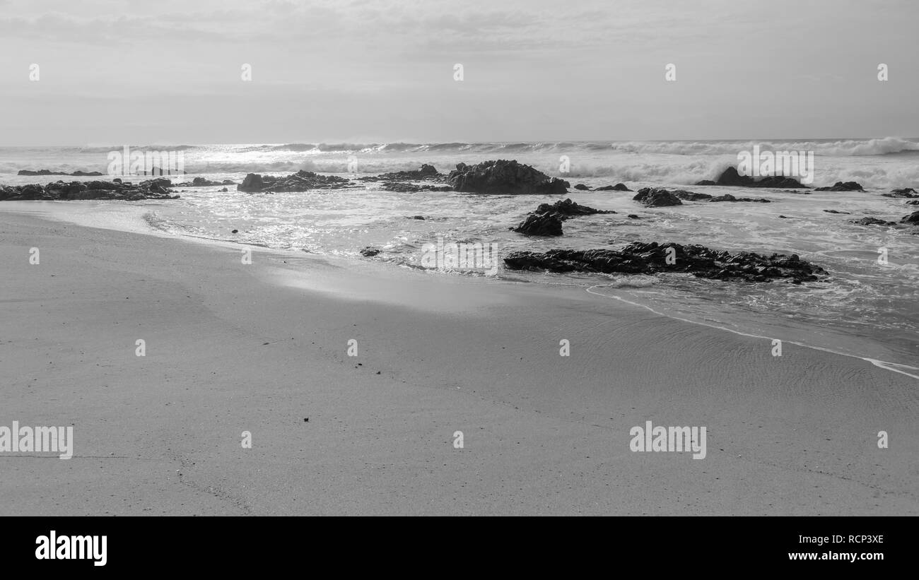 Plage de vent, les vagues de l'océan sauvage matin eaux à horizon avec côte rocheuse cpntrasted paysage blanc noir Banque D'Images