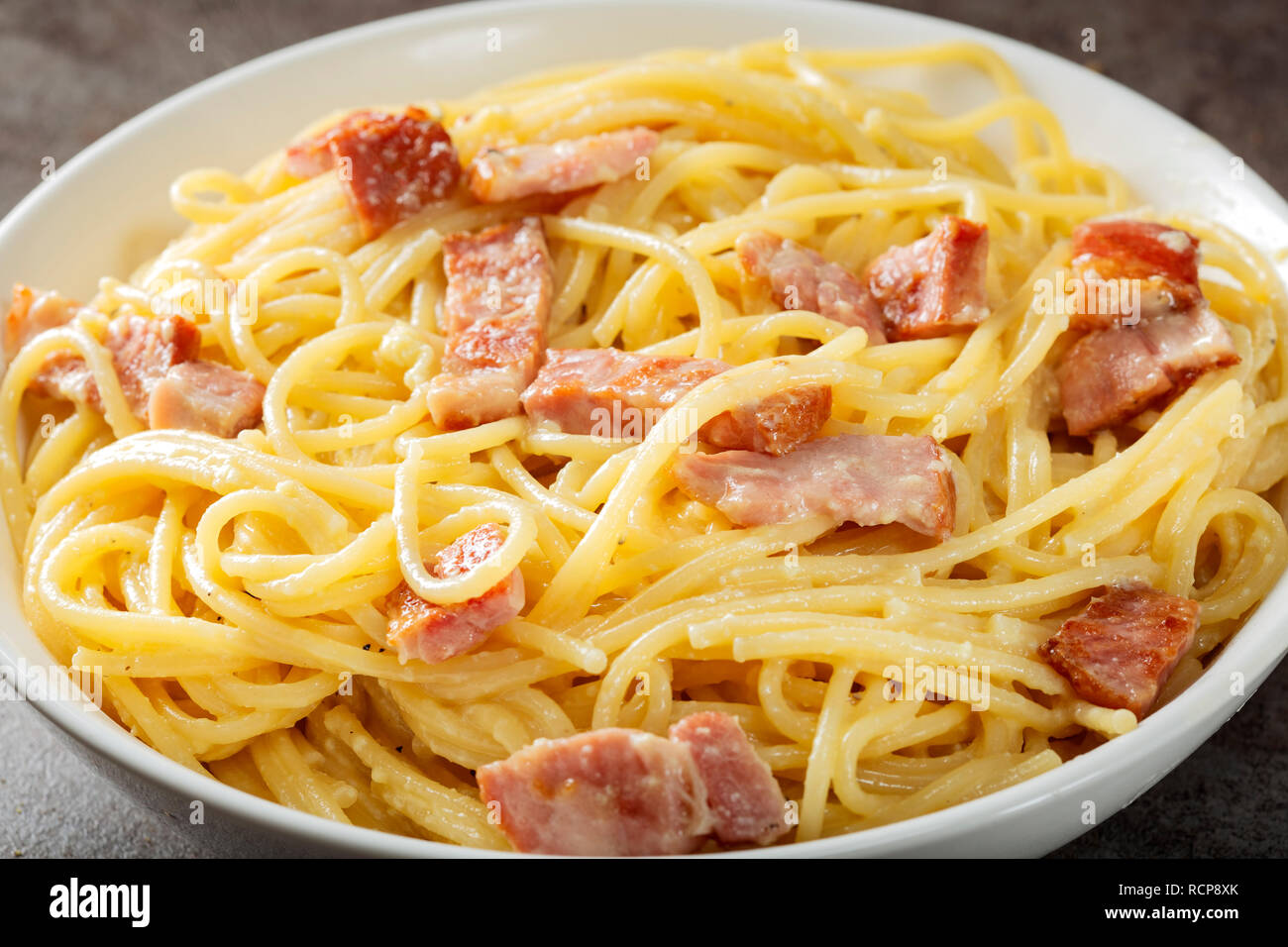 Spaghetti carbonara avec la pancetta, les oeufs et le fromage dans un bol blanc Banque D'Images