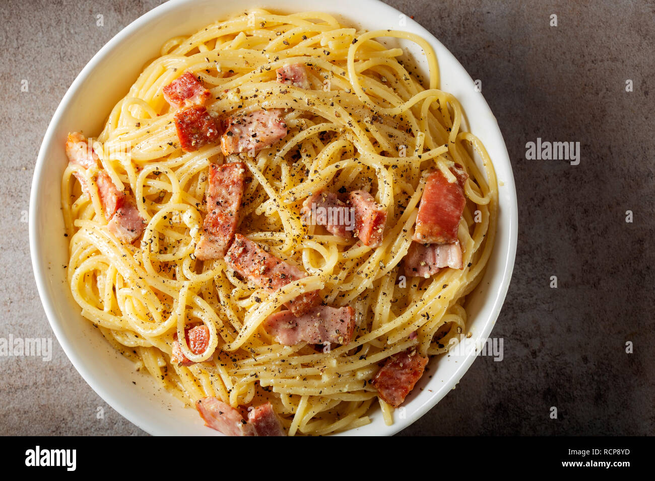 Spaghetti carbonara avec la pancetta, les oeufs et le fromage dans un bol blanc - Vue de dessus Banque D'Images