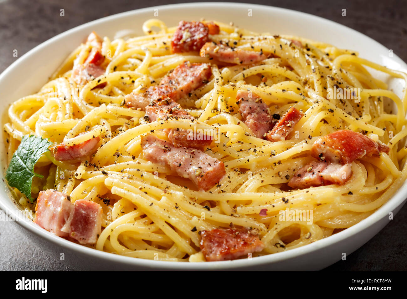 Spaghetti carbonara avec la pancetta, les oeufs et le fromage dans un bol blanc Banque D'Images