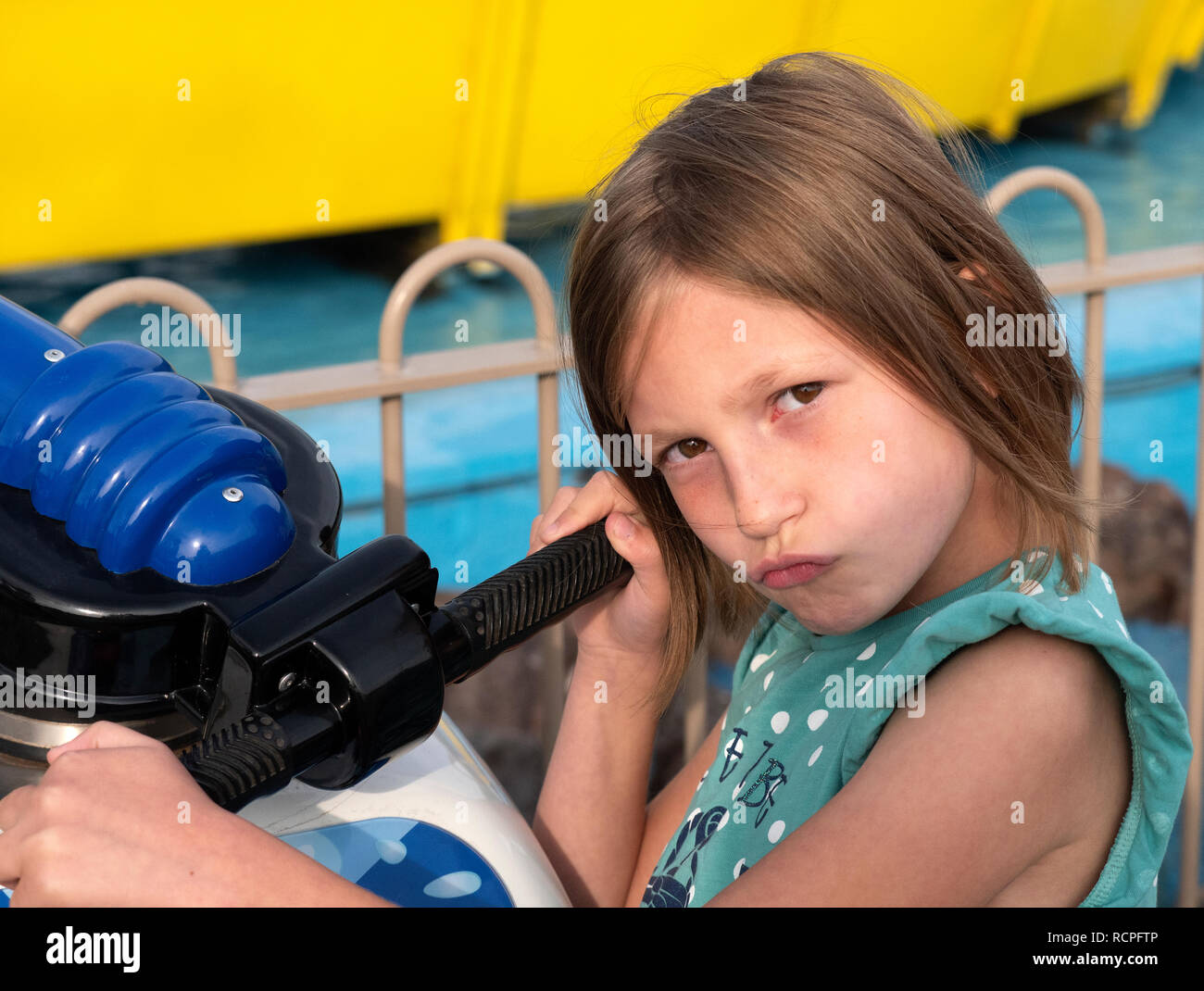 7 ans, fille, posant pour l'appareil photo avec un canon à eau à un parc d'agrément. Banque D'Images