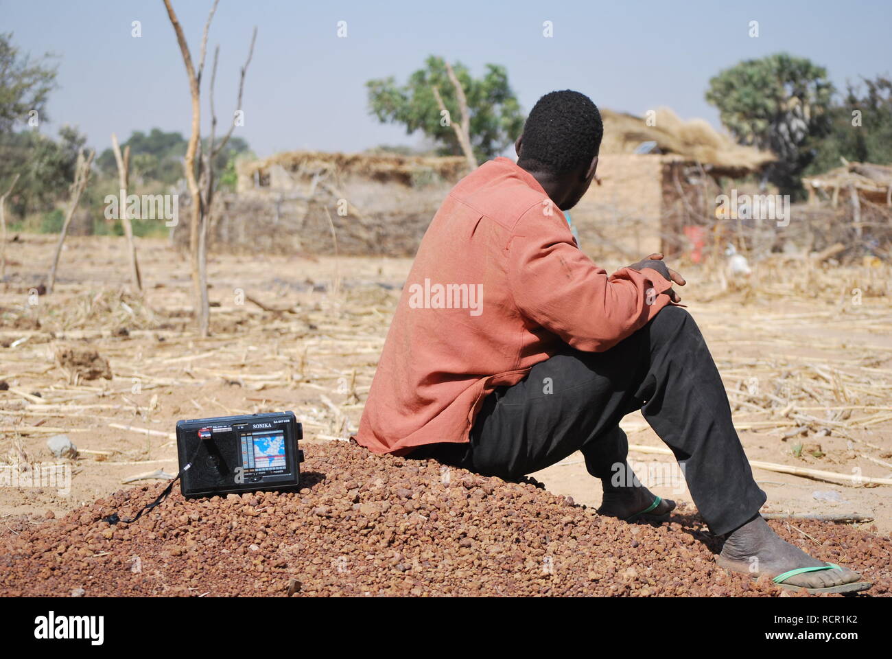 Un homme à l'écoute de sa radio dans un village rural au Niger, Afrique Banque D'Images