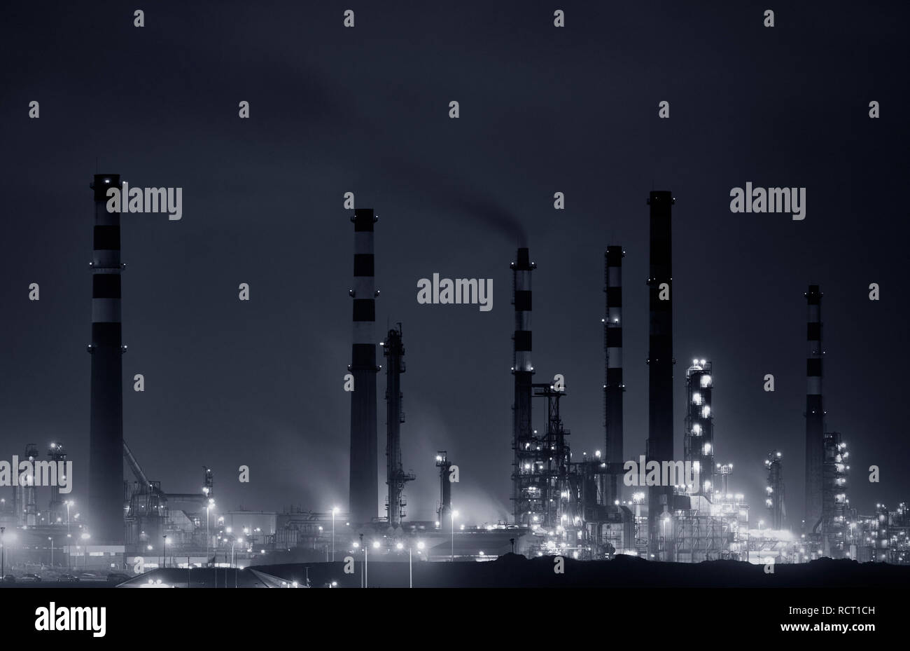Panorama d'une partie d'une grande raffinerie par nuit. Converti en noir et blanc. Tons bleu. Banque D'Images
