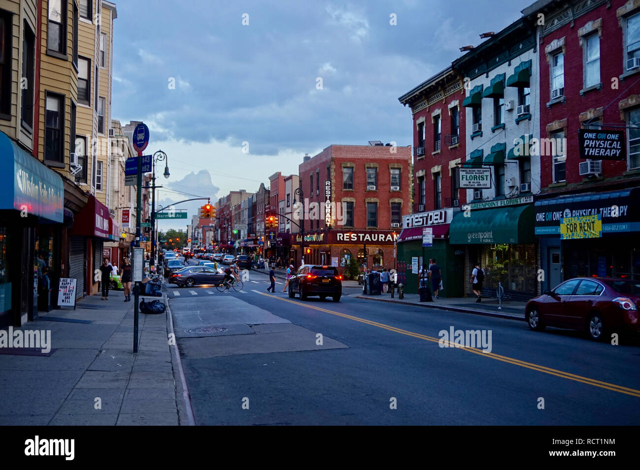 Greenpoint, Brooklyn, NY : vue sur la rue de la ville au crépuscule, avec des feux de circulation, des bâtiments, des voitures, des candélabres. Banque D'Images