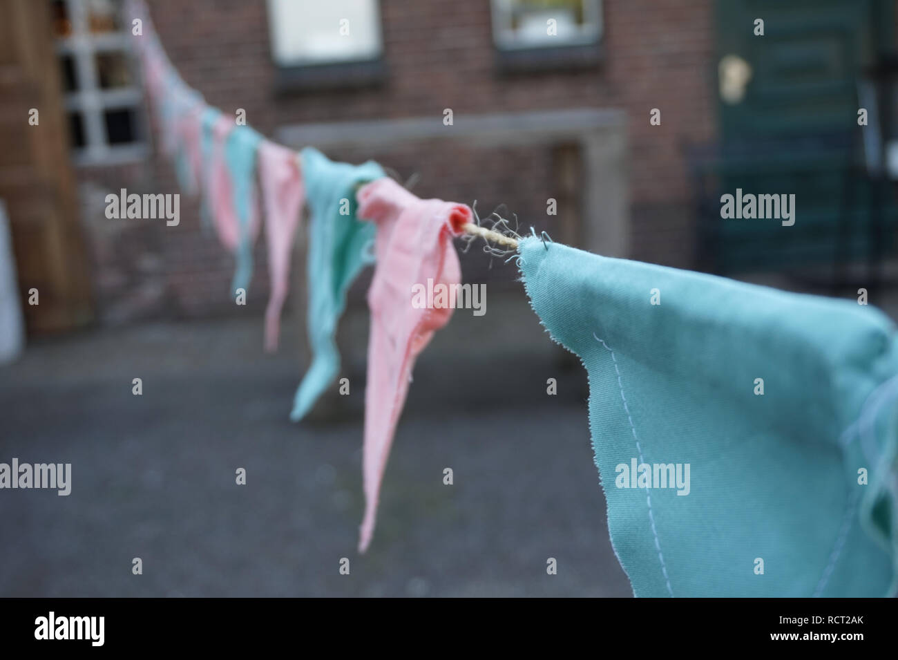 Triangle rose et bleu, fait main tissu garland accroché comme décoration, bâtiment en brique avec en arrière-plan. Mariage de fête ou le sexe révèlent la décoration. Banque D'Images