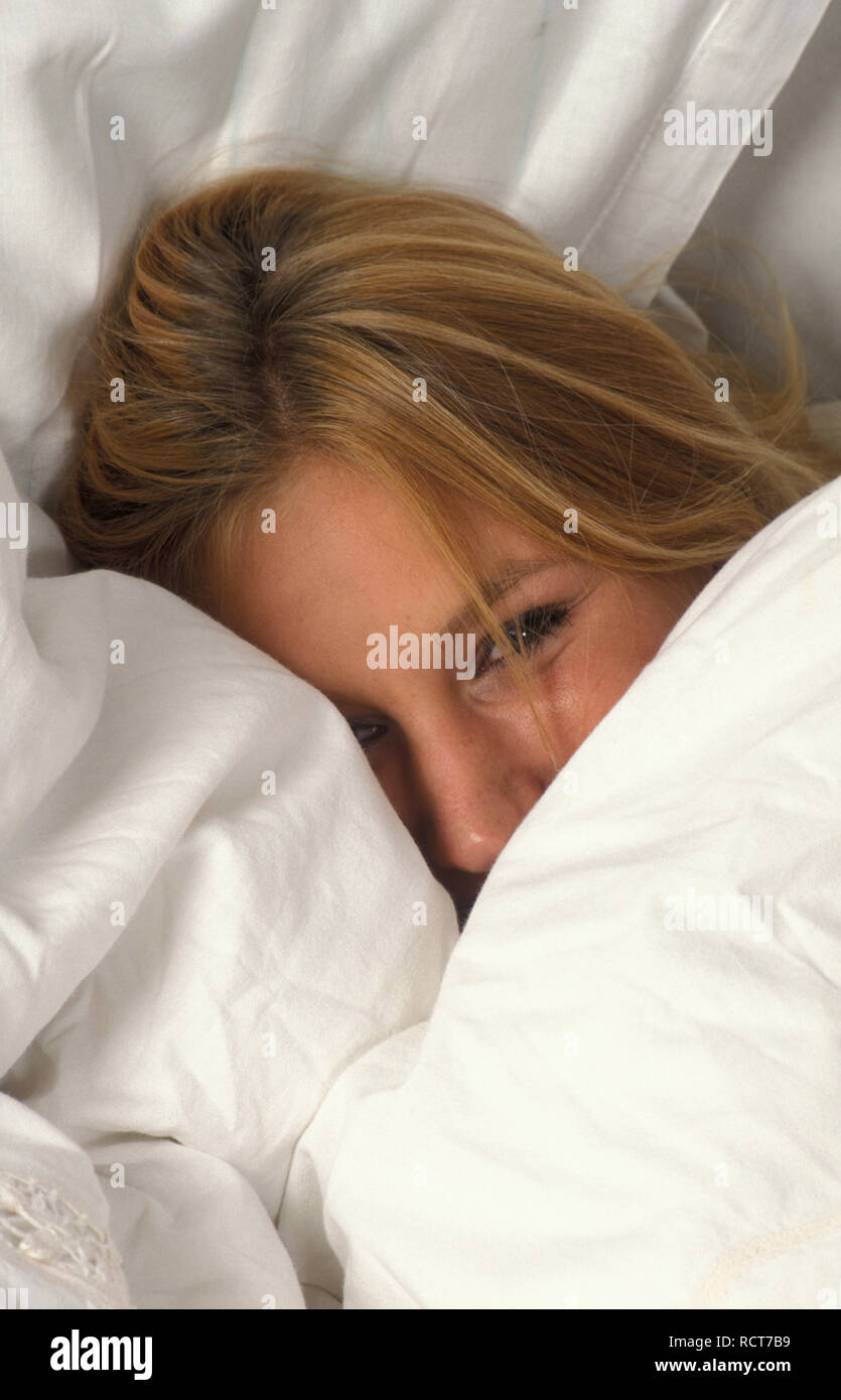 Jeune femme sous les draps blancs Banque D'Images