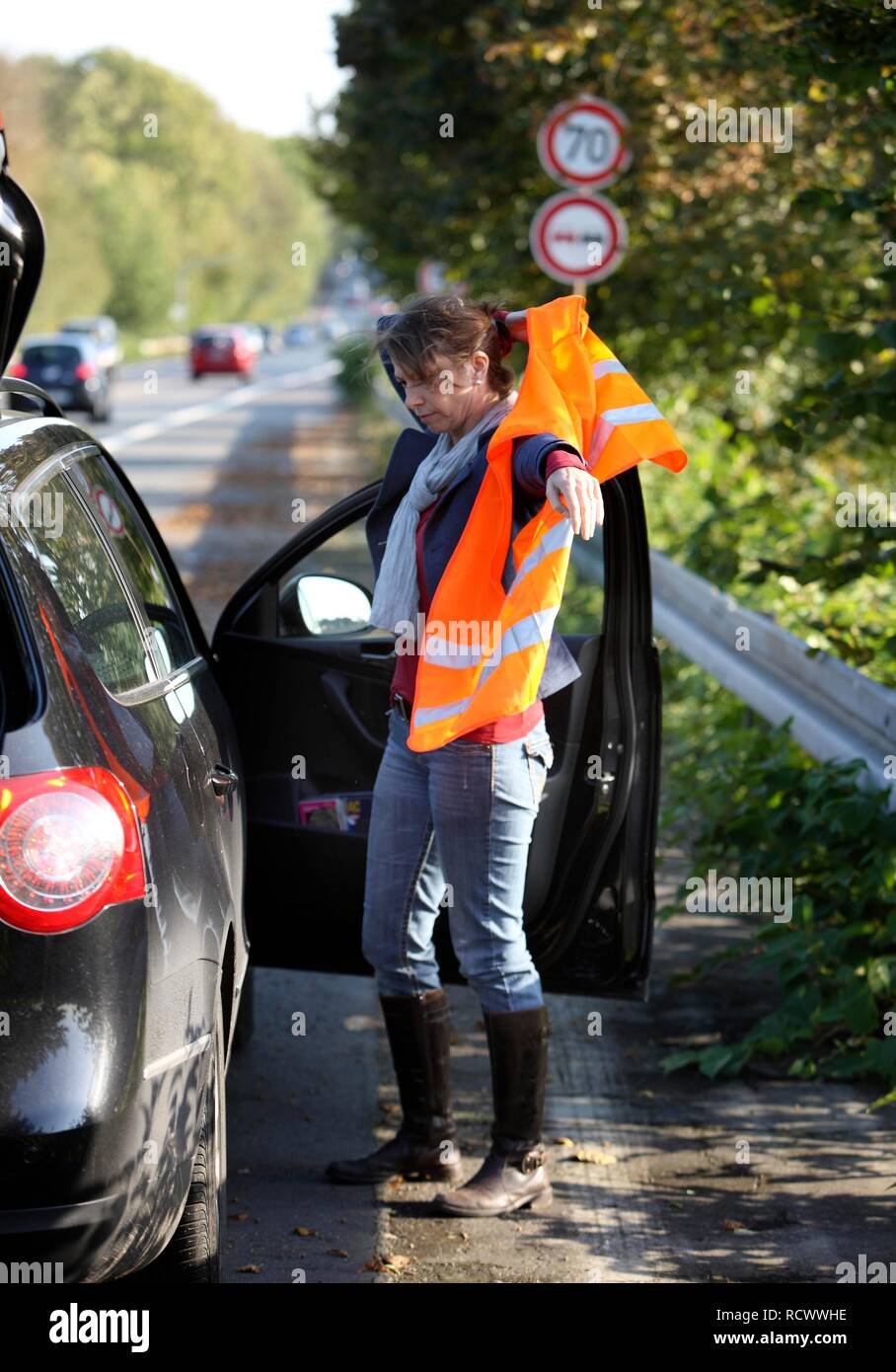 Panne de voiture, la conductrice s'est arrêtée sur la bande d'arrêt d'une route de campagne de mettre un gilet réfléchissant Banque D'Images