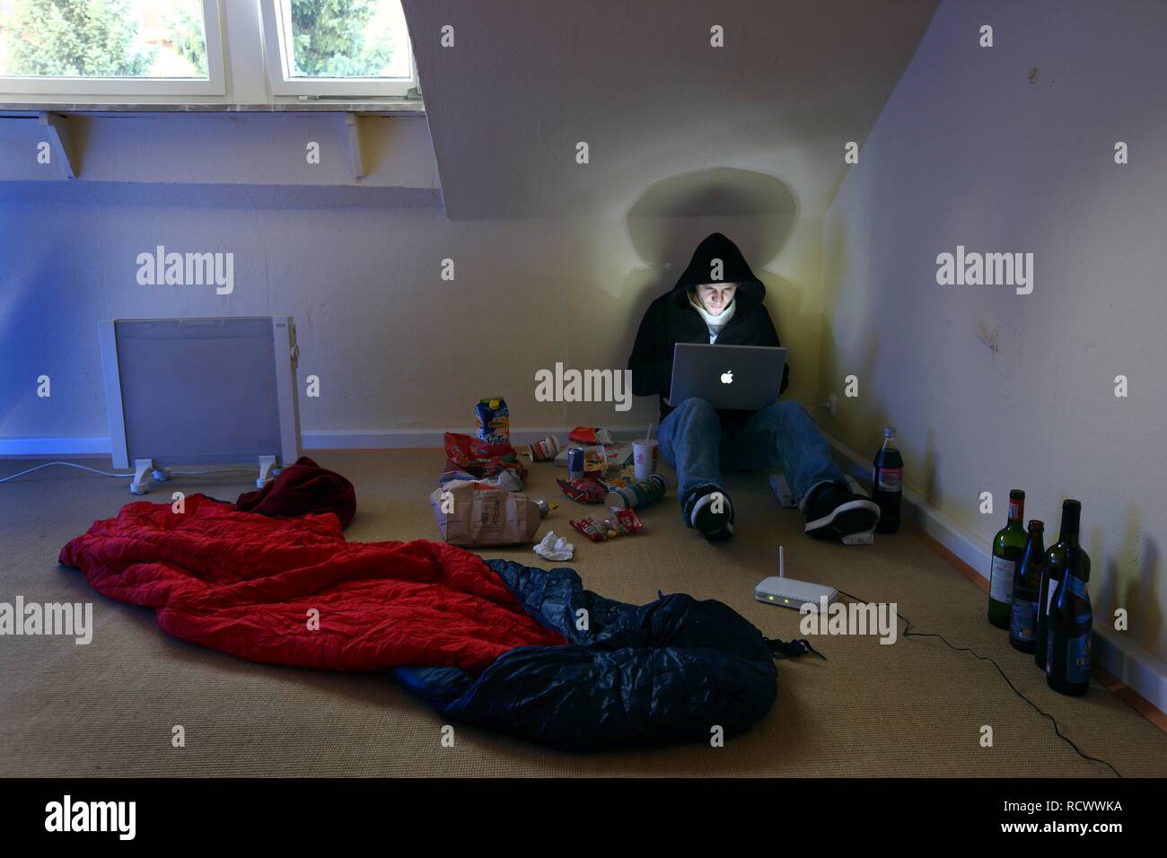 Hacker travaillant sur un ordinateur portable dans une région peu appartement meublé, image symbolique pour le piratage informatique, la criminalité informatique Banque D'Images