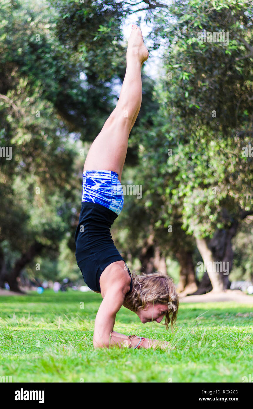 Jeune femme debout sur sa tête, faisant du yoga dans le parc Banque D'Images