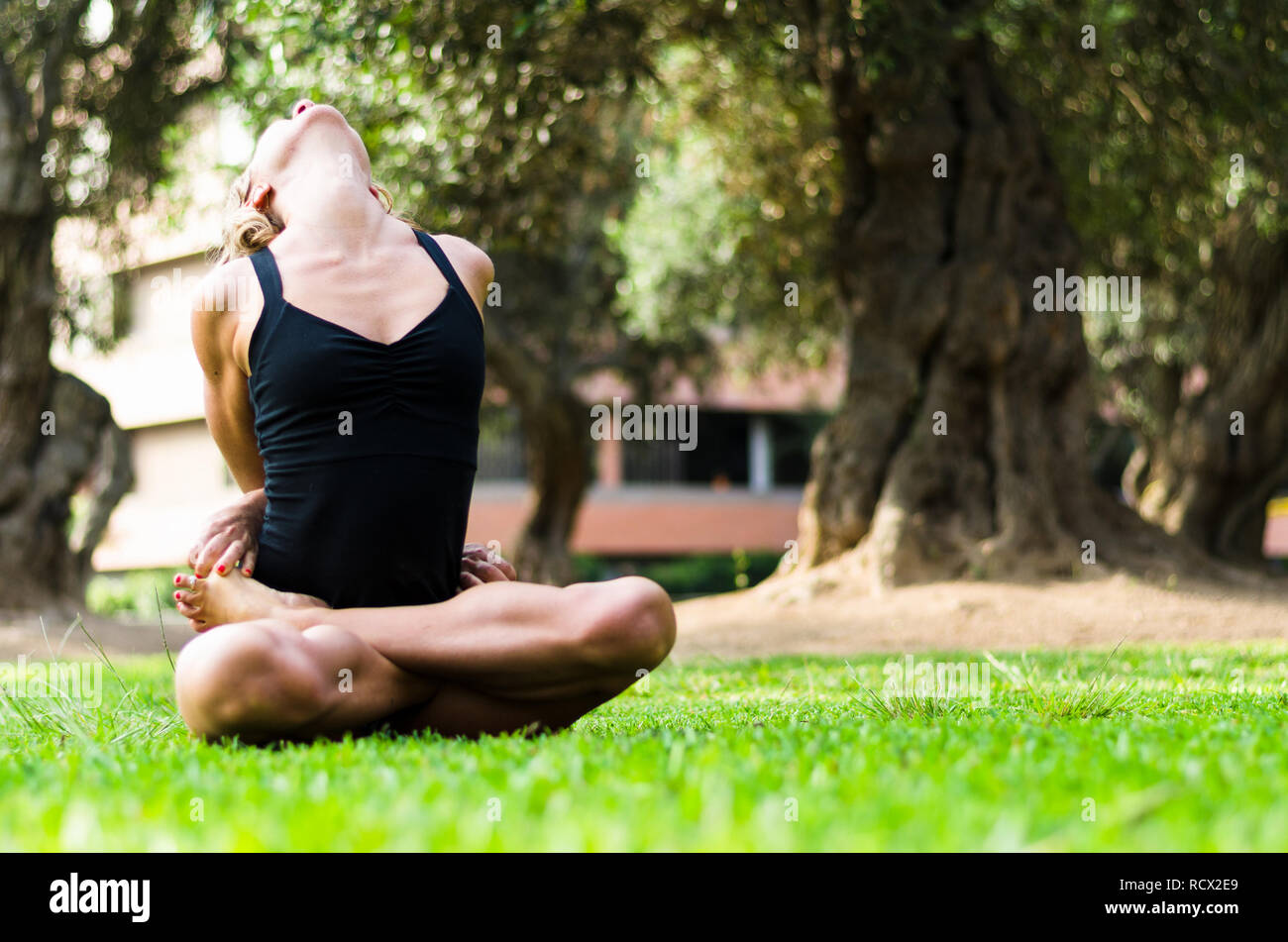 Belle femme pratiquant le yoga dans le parc.La pose Lotus Padmasana Baddha verrouillé Banque D'Images