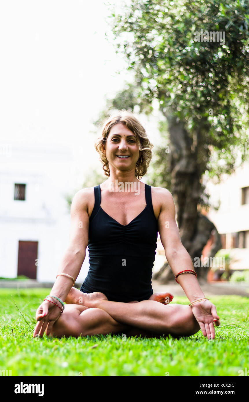 Femme méditant et en pratiquant le Yoga, Lotus pose, le Padmasana. Méditation sur la journée ensoleillée d'automne au parc. Piscine d'entraînement. Banque D'Images