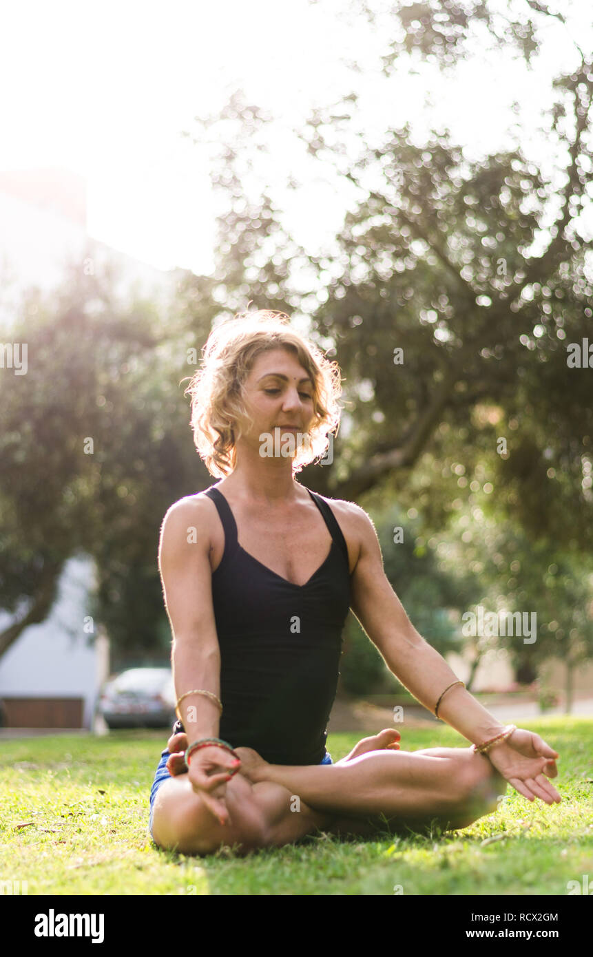 Femme méditant et en pratiquant le Yoga, Lotus pose, le Padmasana. Méditation sur la journée ensoleillée d'automne au parc. Piscine d'entraînement. Banque D'Images