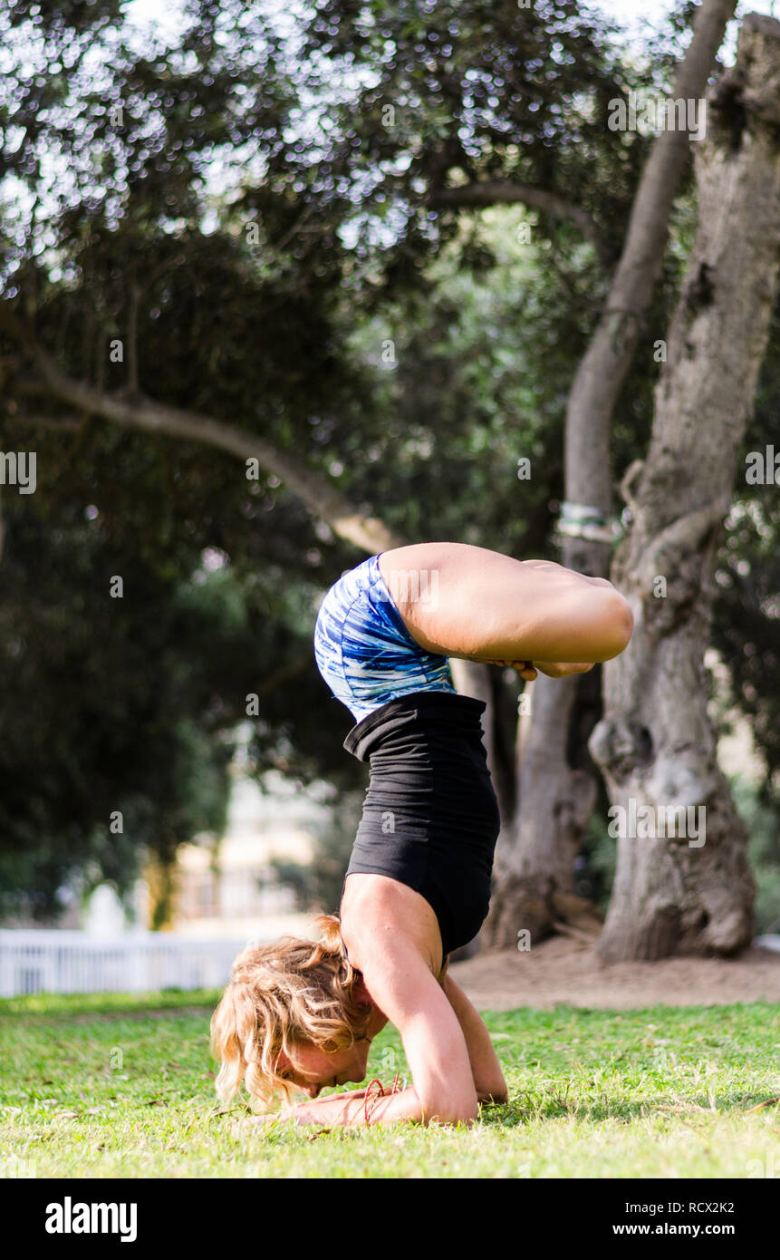 Jeune femme debout sur sa tête, faisant du yoga dans le parc Banque D'Images