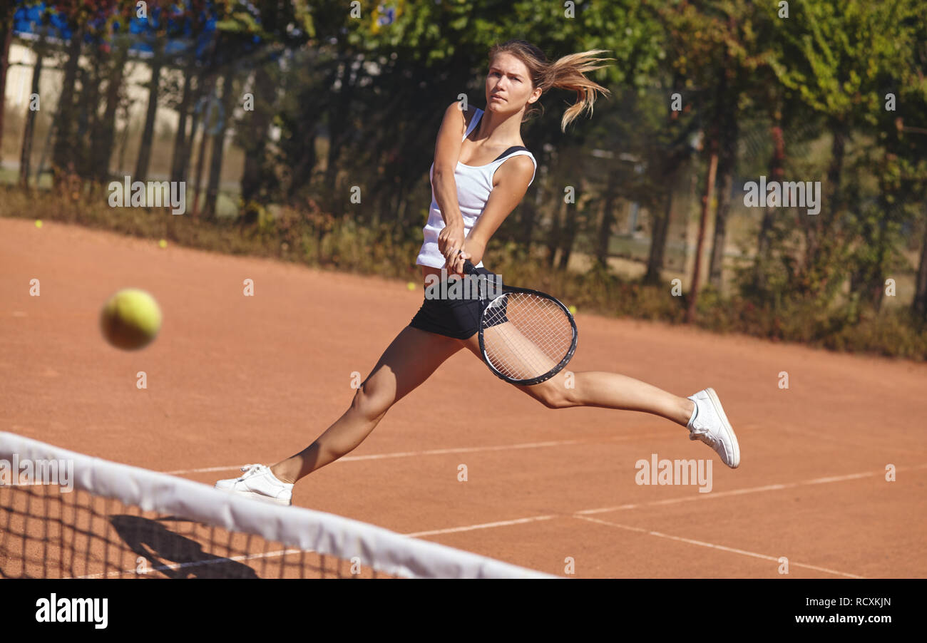 Une jeune fille jouant au tennis sur le court sur une belle journée ensoleillée Banque D'Images