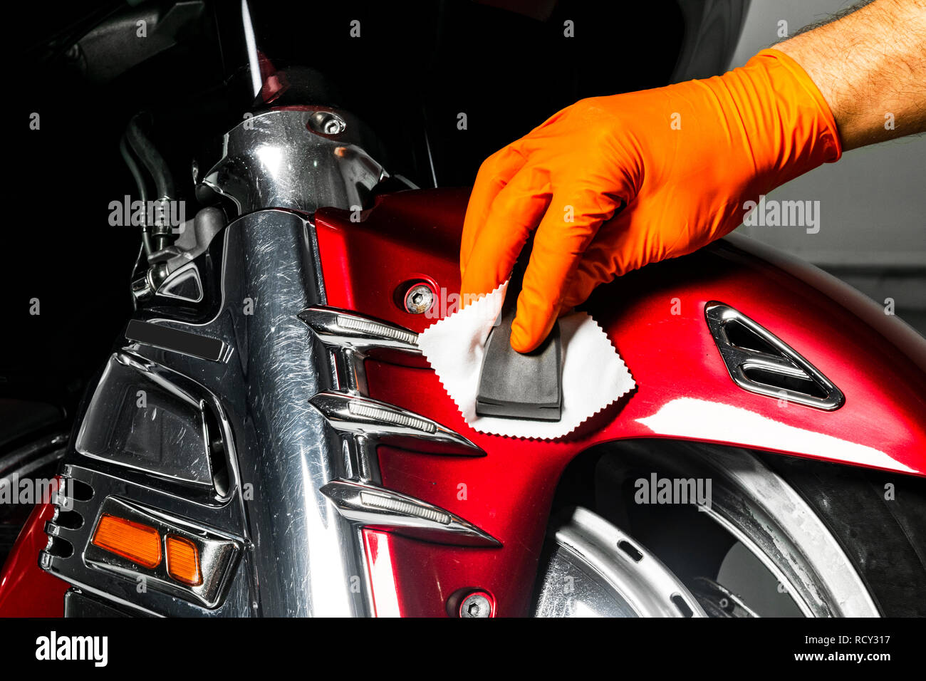 Polish wax voiture mains travailleur l'application de ruban de protection avant le polissage. Meulage et polissage moto. Esthétique auto. L'homme est titulaire d'une polisseuse à l'ha Banque D'Images