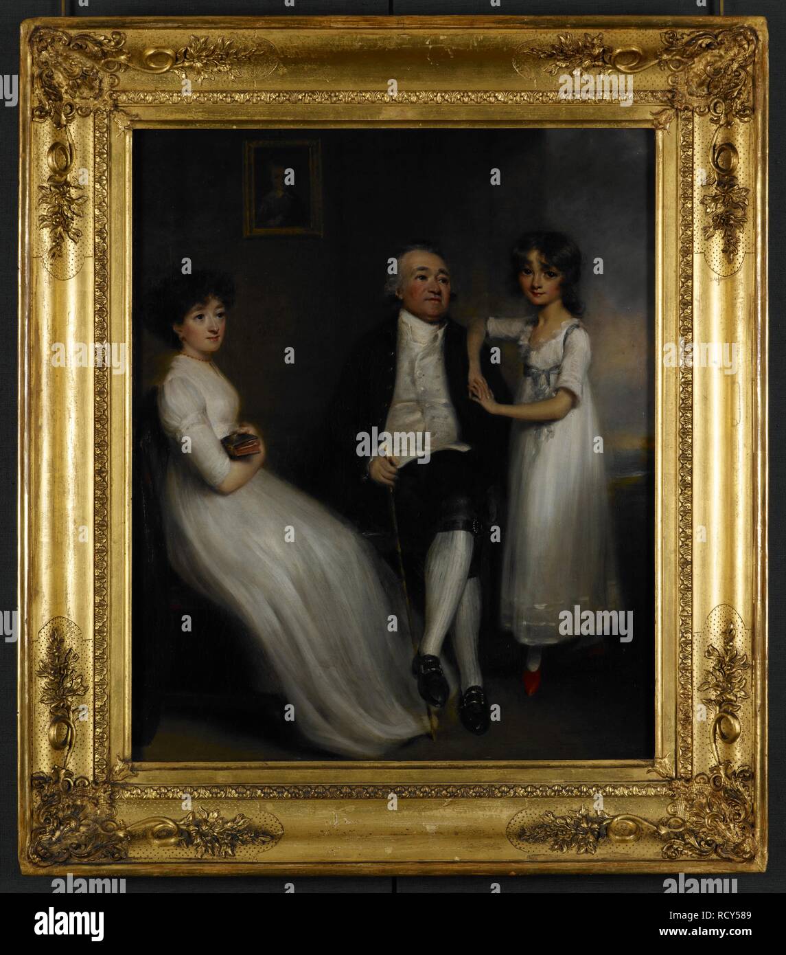 Portrait de Pierre Fombelle (1731-1802) avec sa fille, Lucy (1766-1819) et sa petite-fille Marie (1788-1877), c.1795. Fombelle est assis tenant une canne, sa petite-fille sur sa gauche avec son bras droit sur son épaule, sa fille est assise à sa droite, tenant un livre. Sur le mur derrière eux est le portrait d'un garçon, probablement John Fombelle (1763-1840), Mary's père. c.1795. Peinture à l'huile. Source : Favoriser l'847. Auteur : ANON. Banque D'Images