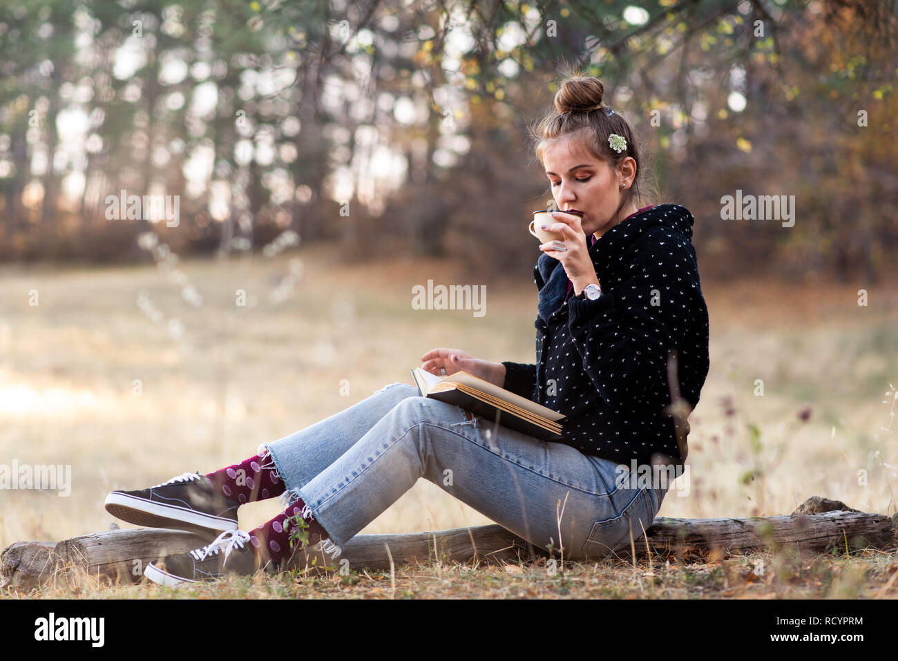 Jeune fille lisant un livre et d'avoir une tasse de café en plein air Banque D'Images