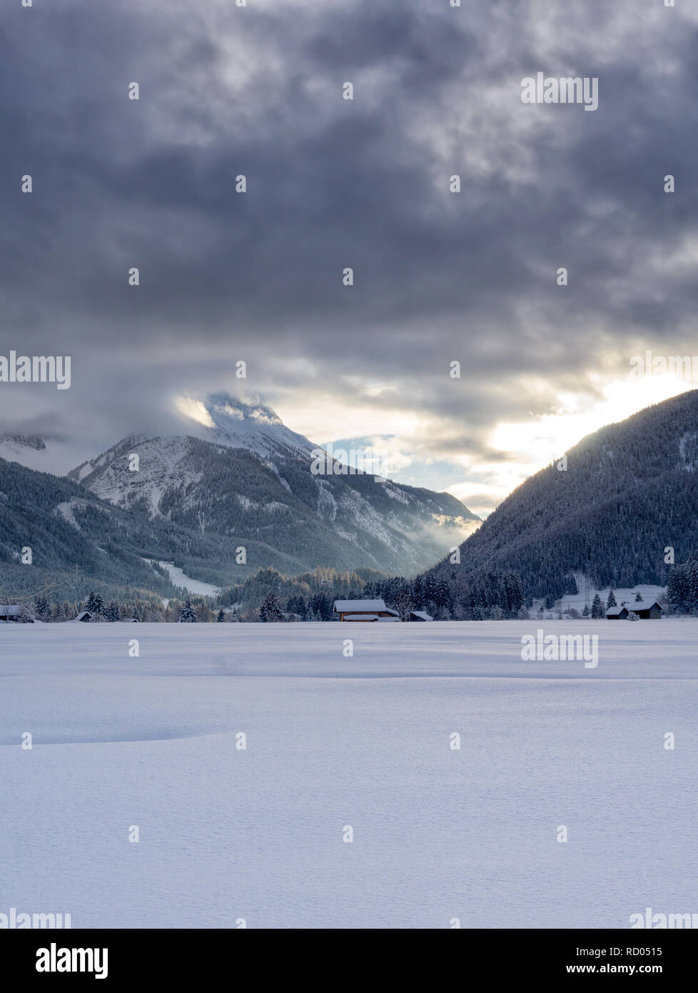 Paysage de montagne d'hiver au crépuscule. Le soleil qui illumine les nuages sombres. Le brouillard est de tomber dans la vallée. Banque D'Images