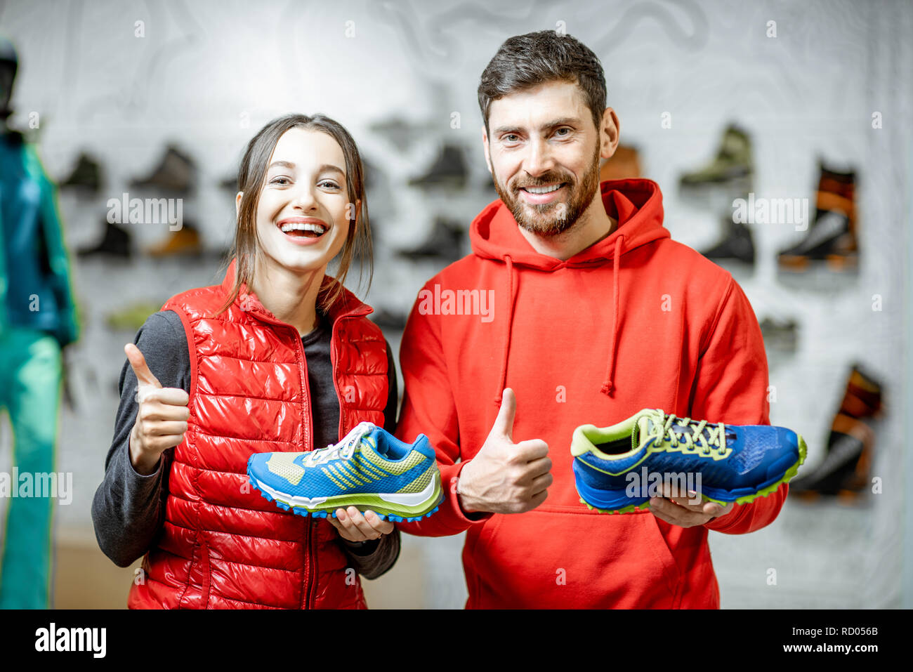 Portrait of a smiling man and woman standing avec chaussures de randonnée dans le magasin de sport moderne Banque D'Images