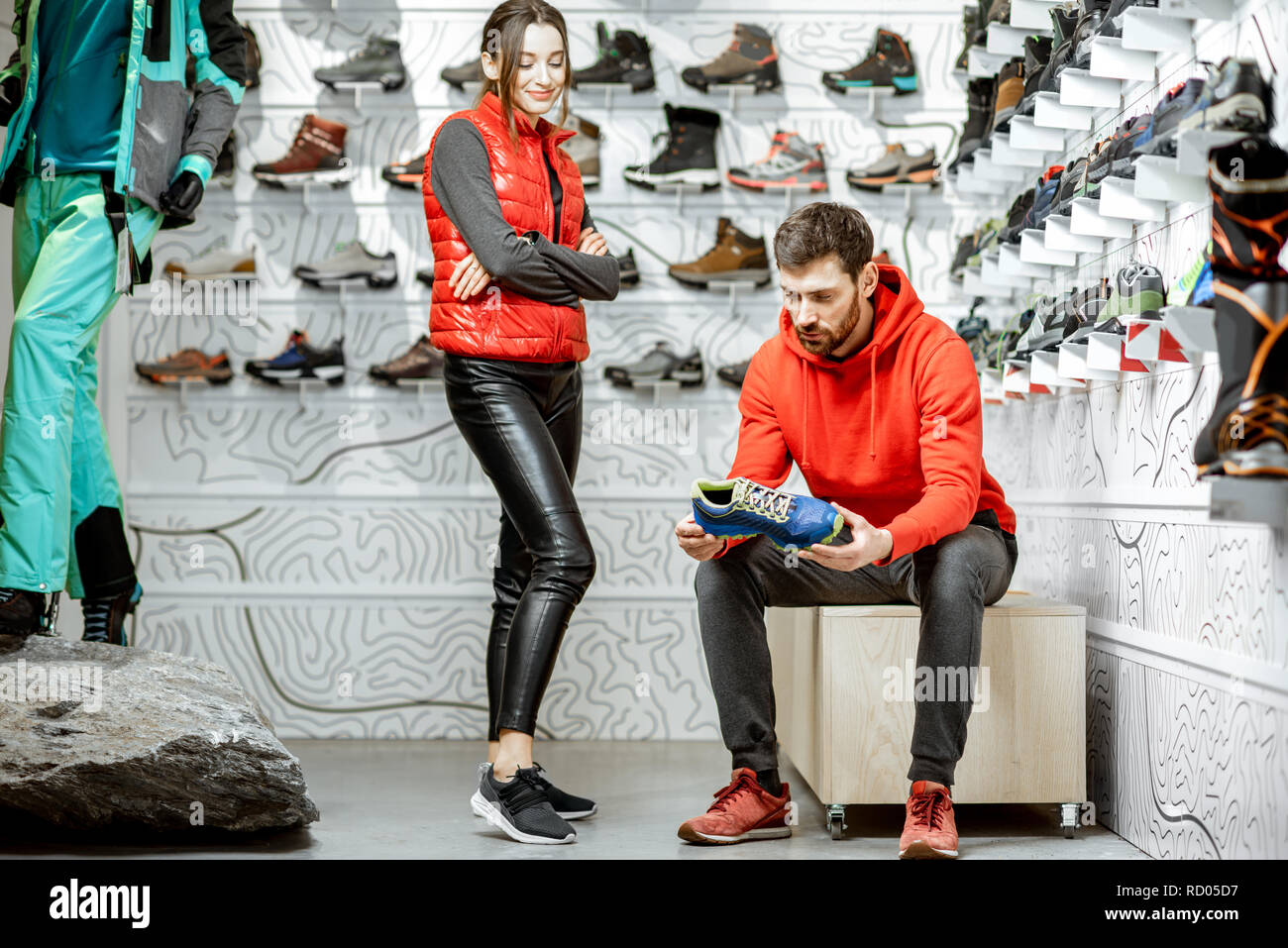 L'homme et de la femme le choix de chaussures de randonnée assis dans le  salon d'essayage de la boutique de sport moderne Photo Stock - Alamy