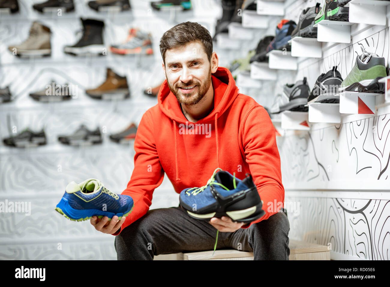 Portrait d'un homme dans le salon d'essayage de la boutique de sport moderne le choix de chaussures de trail pour la randonnée Banque D'Images