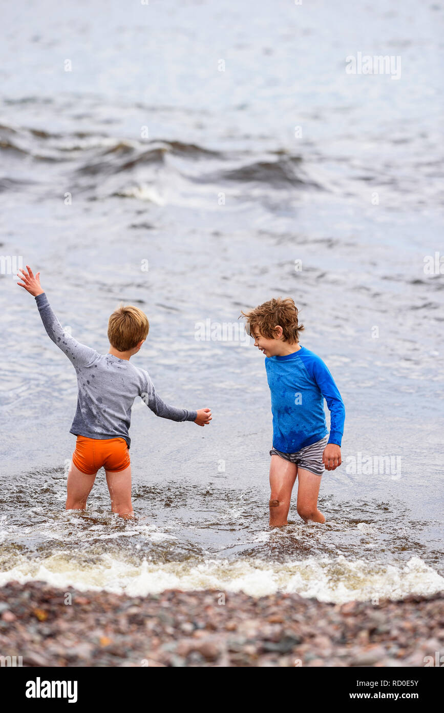 Deux garçons debout genou profondément dans la mer s'amuser, United States Banque D'Images