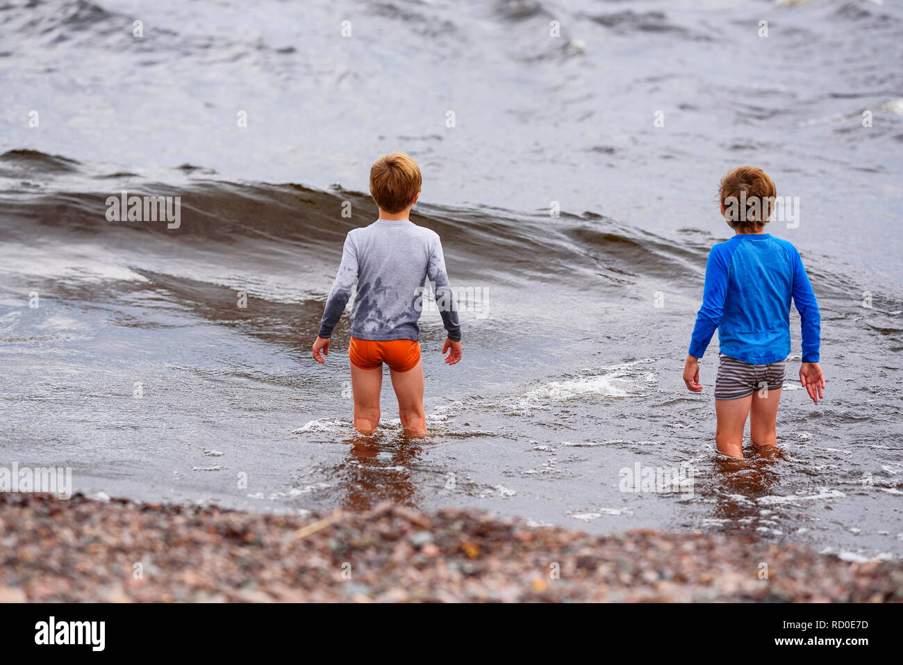 Deux garçons debout genou profondément dans la mer, United States Banque D'Images