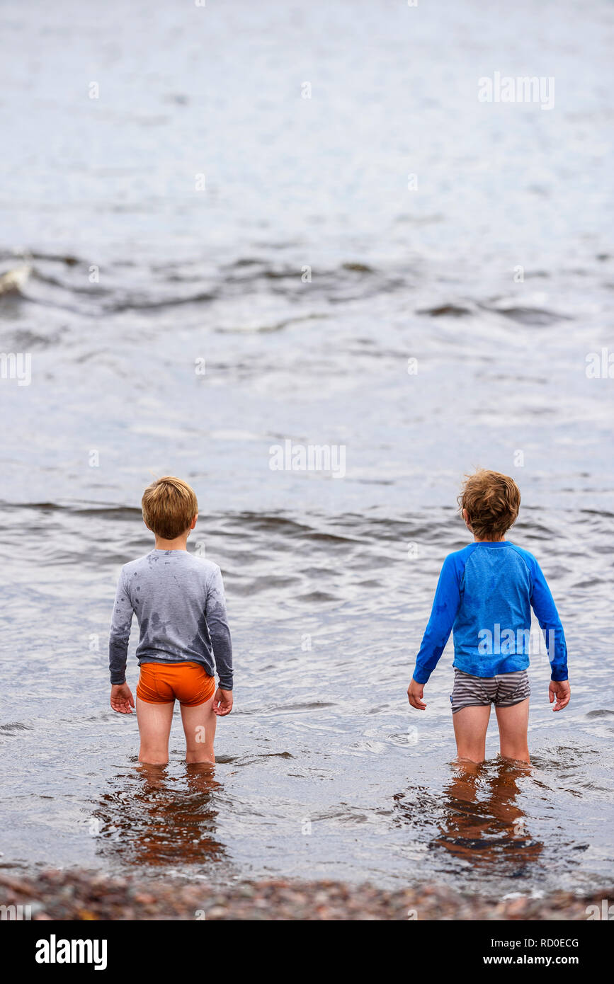Deux garçons debout genou profondément dans la mer, United States Banque D'Images
