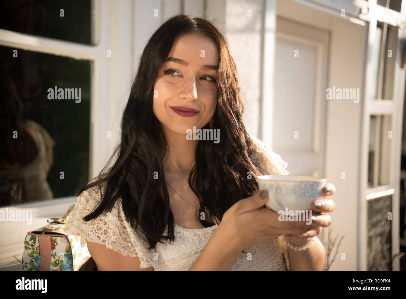 Smiling Woman sitting outdoors de boire une tasse de thé Banque D'Images