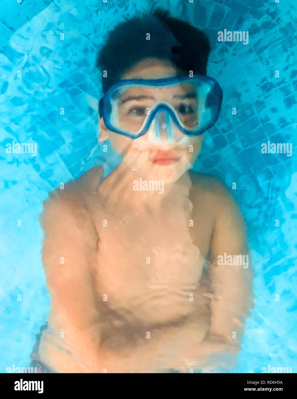 Garçon couché sous l'eau dans une piscine portant un masque de plongée Banque D'Images