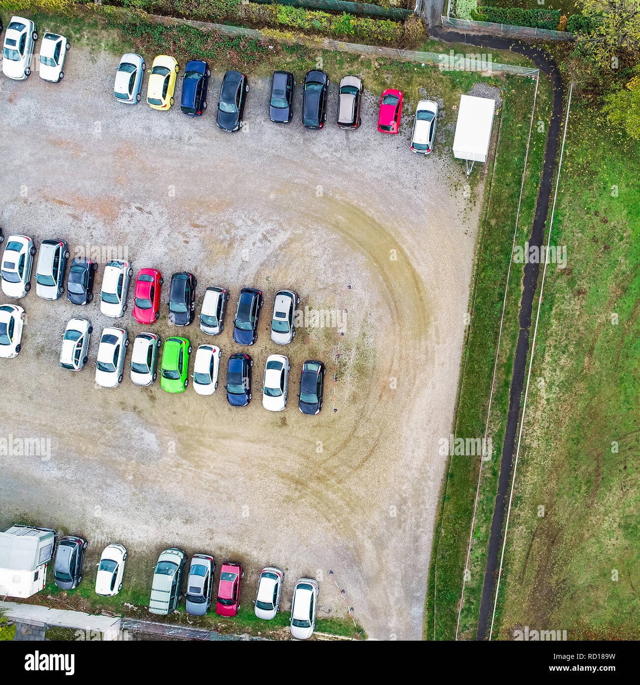 Photo aérienne verticale d'un terrain de stationnement de gravier avec des rangées de voitures en stationnement Banque D'Images