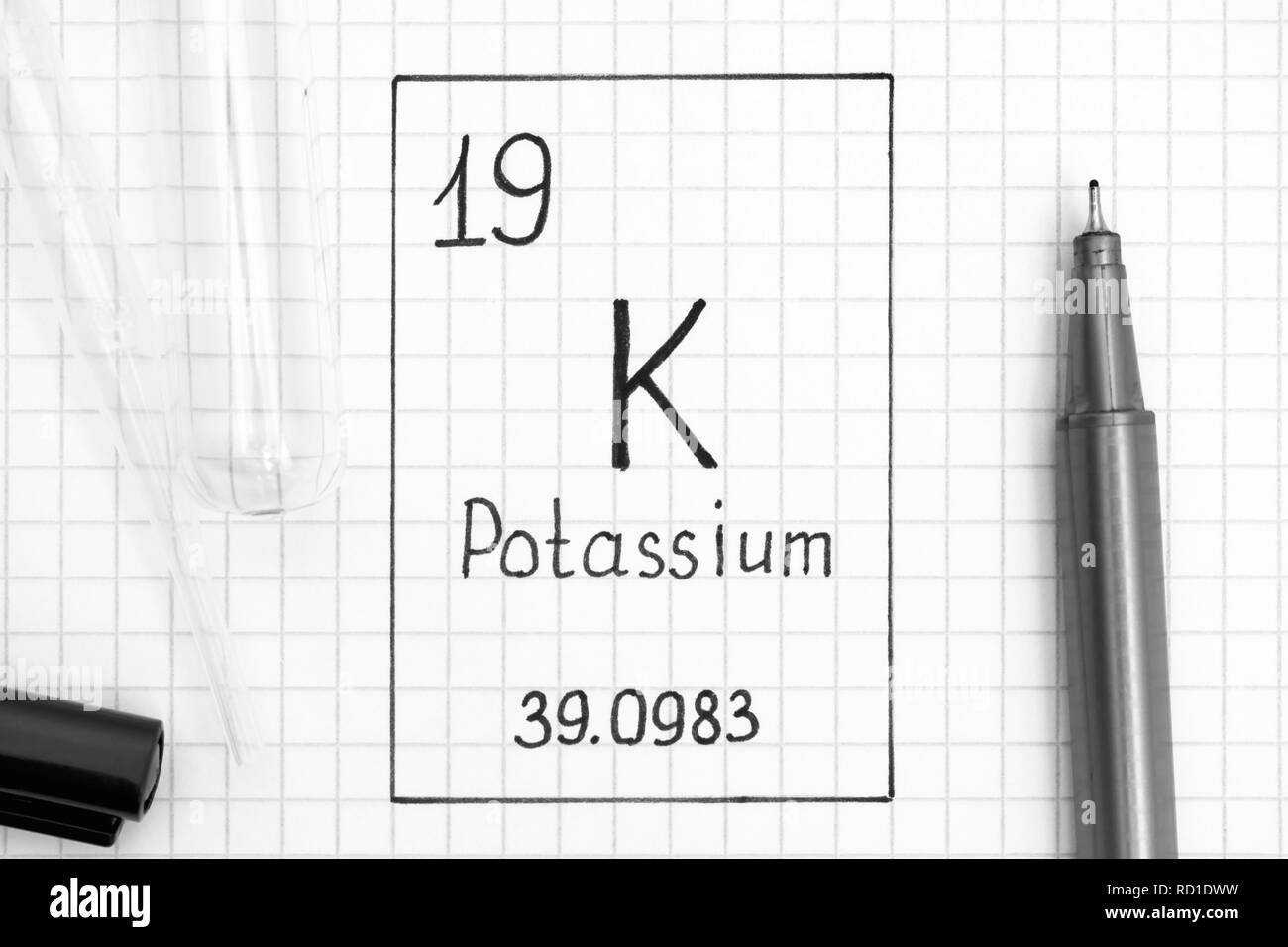 Le tableau périodique des éléments. L'élément chimique de l'écriture Le potassium K avec un stylo noir, tube à essai et pipette. Close-up. Banque D'Images