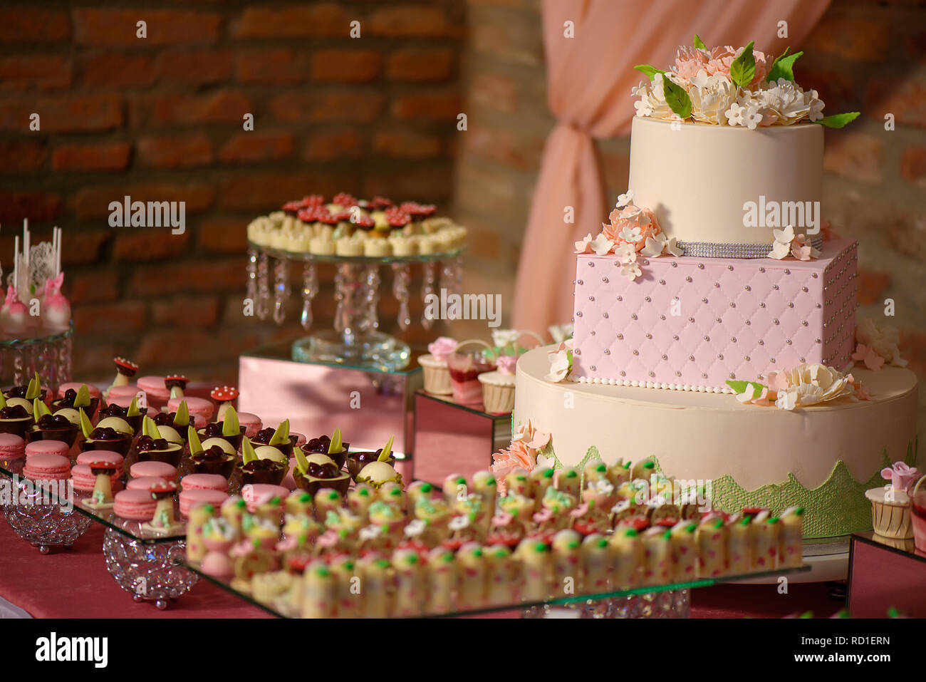 Grand assortiment de mini-gâteaux et un grand gâteau à trois niveaux, orné d'un givrage de velours et fleurs de sucre, délicieux dessert afficher Banque D'Images