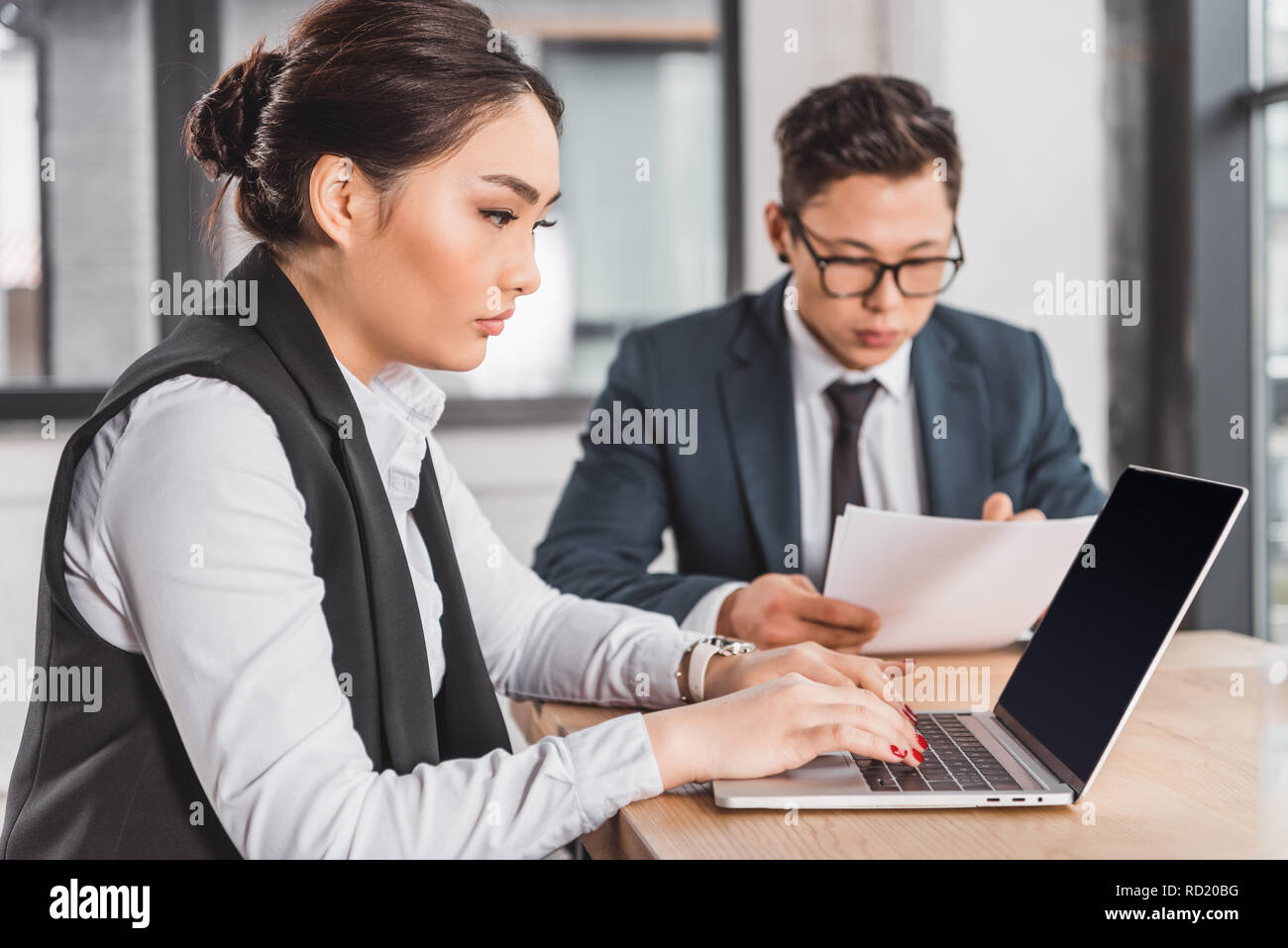 Les jeunes gens d'affaires ciblées kazakh de travail avec ordinateur portable et documents in office Banque D'Images