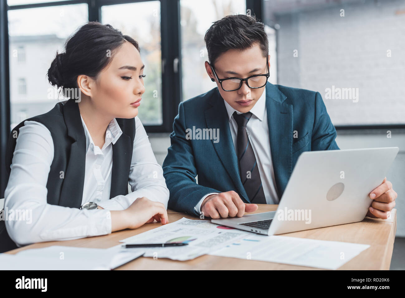 Les jeunes collègues d'affaires axés sur le travail avec ordinateur portable et documents in office Banque D'Images